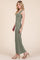 woman wearing a green sleeveless maxi dress and tan heeled sandals, posing sideways