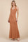 woman wearing a rust-colored sleeveless maxi dress with a fitted silhouette and a flared hem