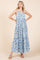 woman wearing a light blue maxi dress with floral print and tiered styling, standing with hands on hips