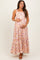 woman wearing a floral pink maternity maxi dress and holding her baby bump