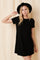 woman wearing a black short sleeve ribbed dress and a black hat, posing against a light background