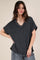 woman wearing a black ribbed v-neck oversized top and gray jeans