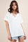 woman wearing a white loose-fitting short sleeve v-neck top and distressed denim shorts