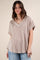 woman wearing a beige oversized v-neck knit top with short sleeves and a relaxed fit