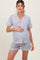 woman wearing a gray short sleeve maternity pajama set with white piping and holding her baby bump