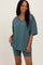 woman wearing a teal oversized v-neck t-shirt and matching bike shorts in a relaxed pose