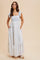 woman wearing a white and light blue floral maxi dress with adjustable tie straps and side pockets