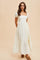 woman wearing a long white puff sleeve dress with a square neckline and tiered bottom