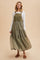 woman wearing an olive green tiered maxi dress with floral embroidery and a white long sleeve top, styled with sandals