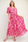 woman wearing a pink floral maxi dress with short sleeves and a tiered skirt, posing gracefully