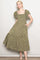 woman wearing a green floral maxi dress with puff sleeves and a square neckline, posing with hands in pockets