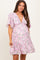 woman wearing a pink floral maternity dress with short flutter sleeves and a deep v-neckline, showing her baby bump
