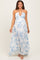 woman wearing a floral print maxi maternity dress in white and blue with a deep neckline and halter straps