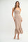 woman wearing a beige textured maxi dress with a fitted bodice and a flounced hem, standing in a neutral setting