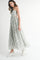 woman wearing a floral print maxi dress with cutout sides and scalloped hem, paired with white sneakers