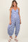 woman wearing a blue floral maternity jumpsuit with a loose fit and spaghetti straps, showcasing her baby bump