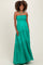 woman wearing a green strapless maternity maxi dress with a halter neck and a flowing tiered skirt, showcasing her baby bump