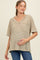 woman wearing a khaki and white striped maternity top with a v-neck and pocket, gently holding her baby bump