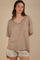 woman wearing a brown and cream striped oversized v-neck t-shirt with a front pocket and distressed white shorts