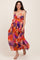woman wearing a vibrant floral maternity maxi dress with a tie waist and a flowing silhouette, showcasing her baby bump
