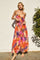 woman wearing a colorful floral maxi dress with spaghetti straps and a tied detail at the waist