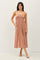 woman wearing a rust-colored patterned maxi dress with adjustable straps and pockets