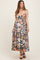 woman wearing a navy floral maternity maxi dress with a tie front and spaghetti straps, showcasing her baby bump