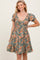 woman wearing a green floral print short dress with puff sleeves and a smocked bodice