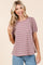 woman wearing a mauve and cream striped short sleeve top with puff sleeves, smiling and touching her hair