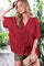 woman wearing a burgundy oversized button-up shirt with short sleeves and styled with khaki shorts and a clutch purse