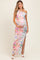 woman wearing a pastel floral print one-shoulder maternity gown, showing her baby bump with a side slit detail