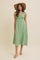 woman wearing a green sleeveless midi dress with tie straps and button detailing, styled with a wide-brimmed hat and sandals