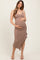 woman wearing a taupe maternity dress with a fitted silhouette and ruffled hem, holding her baby bump