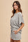 woman wearing a grey textured short sleeve romper with a relaxed fit and tie waist, featuring side pockets