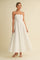 woman wearing a white spaghetti strap maxi dress with a fitted bodice and flowing skirt