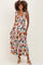 woman wearing a floral print maternity maxi dress with ruffle straps and tiered skirt, smiling with a baby bump visible