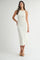 woman wearing a cream-colored ribbed midi dress with a halter neckline and a fitted silhouette