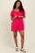 woman wearing a bright pink short-sleeve romper with a tie front detail and relaxed fit