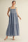 woman wearing a light blue maxi dress with adjustable shoulder straps and a tiered skirt