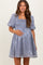 woman wearing a light gray puff sleeve maternity dress with a square neckline and smocked bodice, showing her baby bump