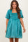 woman wearing a teal maternity dress with puff sleeves and a smocked bodice, showcasing a baby bump