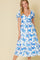 woman wearing a white floral midi dress with blue print and puff sleeves, posing against a light background
