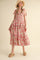 woman wearing a floral print maxi dress with tiered ruffles and bow straps, styled with a straw hat and sandals