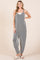 woman wearing a striped gray and white jumpsuit with a loose fit and side pockets, standing with a relaxed pose
