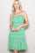 woman wearing a green floral sundress with spaghetti straps and a ruffled hem