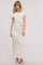 woman wearing a beige short sleeve maxi dress with a side knot detail and a thigh slit