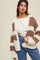 woman wearing a chunky knit cardigan with cream and brown stripes over a white top and high-waisted jeans