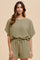 woman wearing an olive green textured short sleeve romper with a drawstring waist