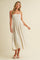 woman wearing a light beige spaghetti strap maxi dress with pleats and a flowy silhouette