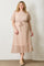 woman wearing a light pink floral plus-size midi dress with short sleeves and a tie waist detail
